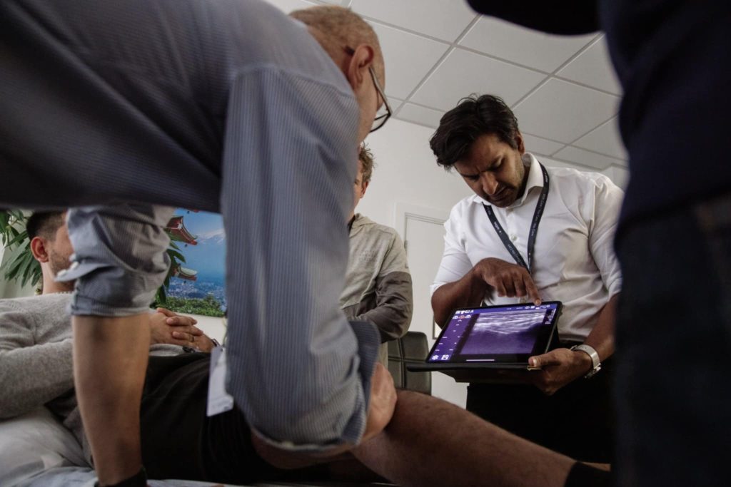 Physiotherapist performing specialist ultrasound guided procedure on the knee joint